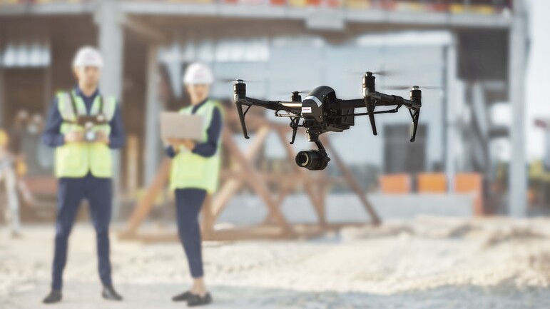 Innovationen von Dussmann Drohne auf einer Baustelle mit Dussmann-Mitarbeitenden